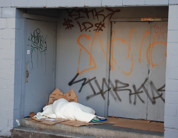 A person sleeps on cardboard outside.