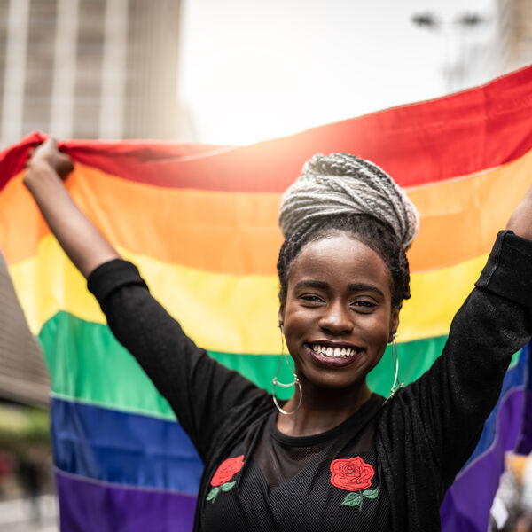 Black woman holding up a rainbow pride flag